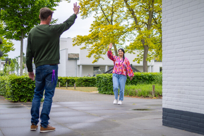 Twee begeleiders gehandicaptenzorg die elkaar zwaaiend groeten op een woongroep