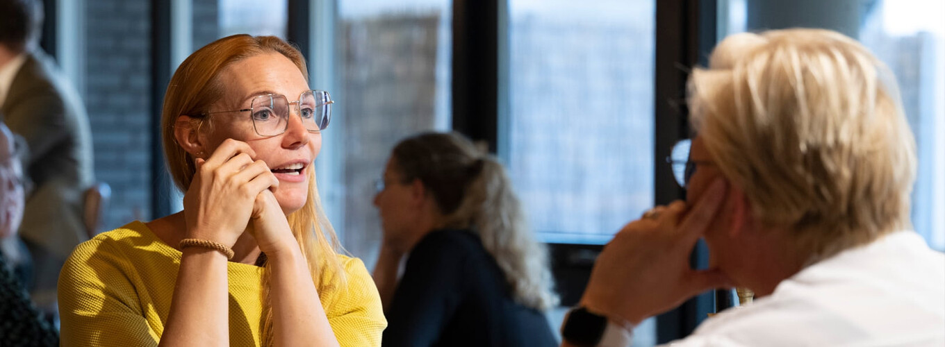 Twee vrouwen zitten aan tafel en praten tegen elkaar