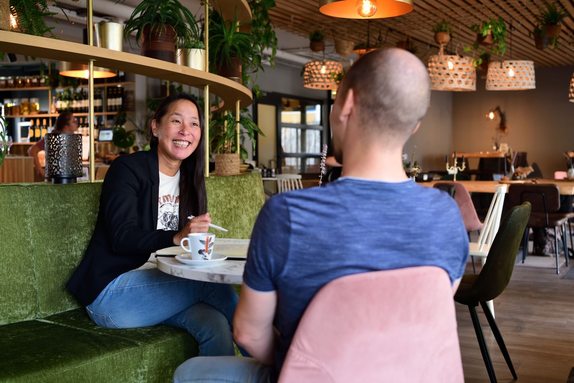 Trainer Tessa zit aan tafel en is in gesprek met een deelnemer.