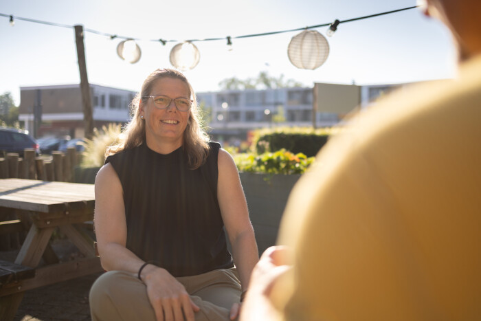 Zorgmanager Miranda is in een tuin in gesprek met iemand en glimlacht.