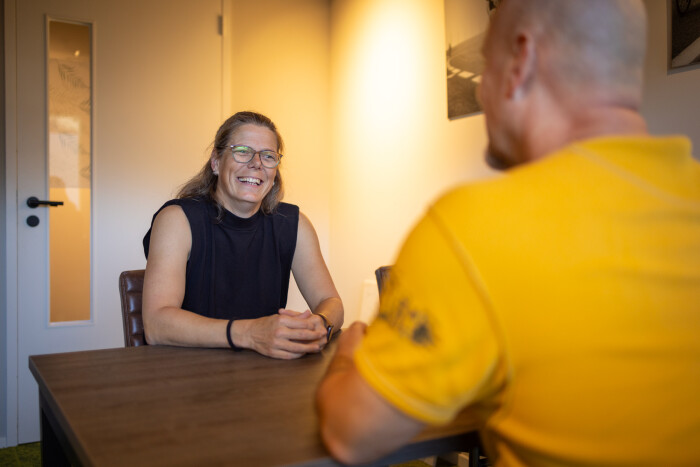 Zorgmanager Miranda zit samen met een andere begeleider aan tafel, ze lacht.