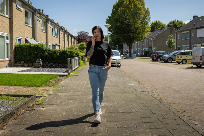 Zorgmanager loopt over straat en is in gesprek aan de telefoon.