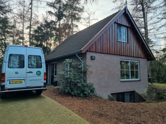 Een vakantiehuisje met links daarvan een Bartimeus busje.