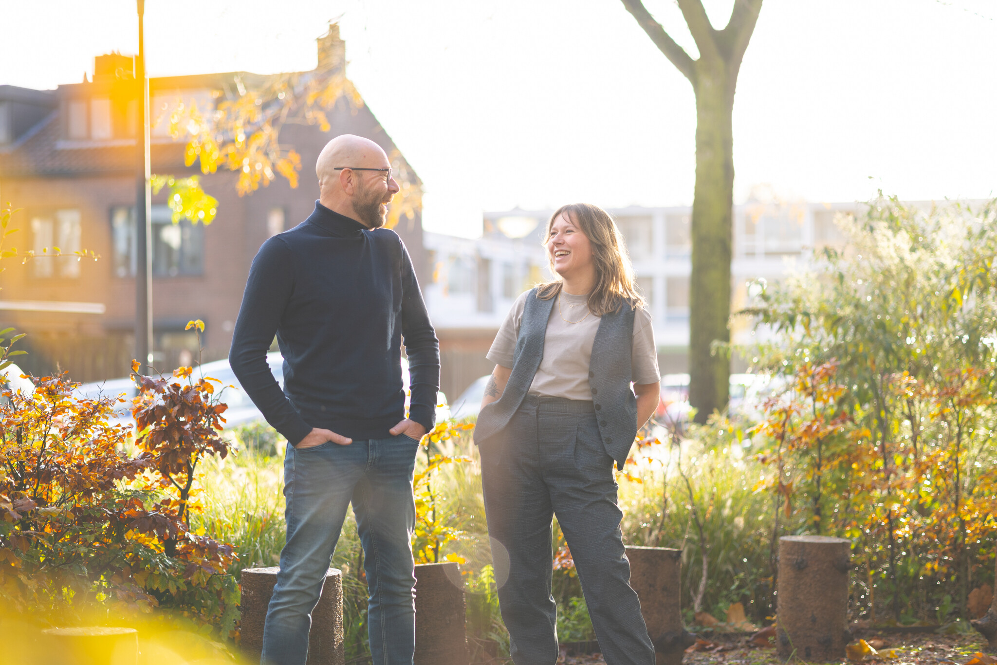 Frits en Elisa staan buiten met hun handen in hun zij. Ze glimlachen naar elkaar.